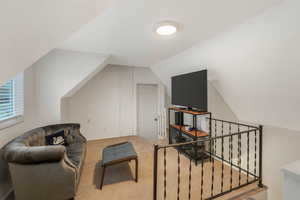 Sitting room with lofted ceiling and carpet flooring