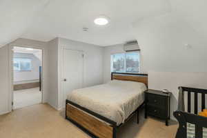 Bedroom with multiple windows, lofted ceiling, and an AC wall unit