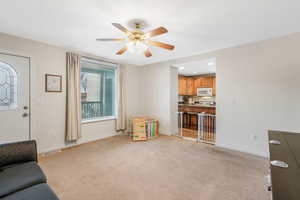 Carpeted living room featuring ceiling fan