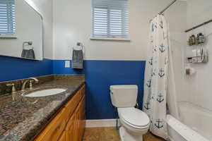 Full bathroom featuring vanity, shower / bathtub combination with curtain, tile patterned floors, and toilet