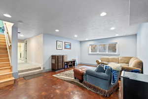 Living room with concrete flooring, washer / dryer, and a textured ceiling