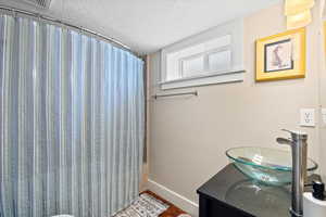 Bathroom featuring vanity, shower / tub combo, and a textured ceiling