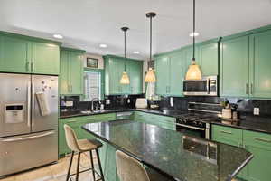 Kitchen with pendant lighting, sink, a kitchen breakfast bar, stainless steel appliances, and a center island