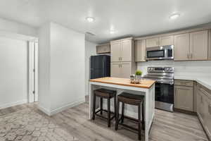 Kitchen with appliances with stainless steel finishes, butcher block countertops, and light hardwood / wood-style flooring