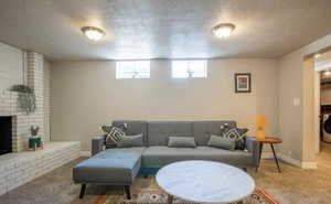 Living room with washer / dryer, a brick fireplace, carpet, and a textured ceiling