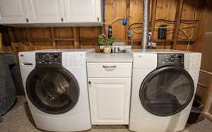 Clothes washing area with wooden walls, washing machine and dryer, and cabinets