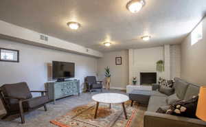 Carpeted living room with a brick fireplace and a textured ceiling