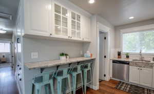 Kitchen featuring white cabinetry, dishwasher, sink, and dark hardwood / wood-style floors