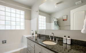 Bathroom with vanity, shower / bathtub combination with curtain, and a wealth of natural light