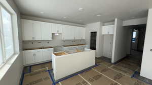 Kitchen with a center island, white cabinets, and a textured ceiling