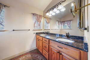 Bathroom with vanity ,with double sinks vaulted ceiling, and tile patterned floors