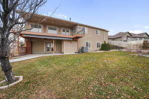 Back of property with central AC, a lawn, a patio, and a balcony