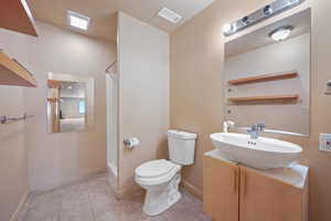 Bathroom with vanity, toilet, tile patterned flooring, and a shower