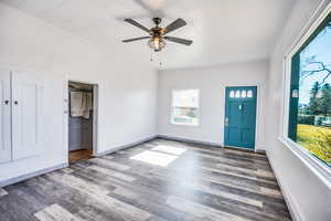 Entryway with dark wood-type flooring, ornamental molding, and ceiling fan