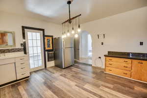 Kitchen featuring sink, tasteful backsplash, stainless steel fridge, dark hardwood / wood-style flooring, and pendant lighting