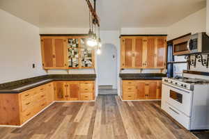 Kitchen featuring a baseboard heating unit, decorative light fixtures, dark hardwood / wood-style floors, and gas range gas stove