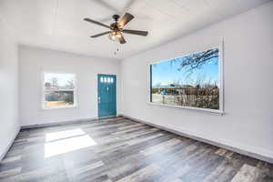 Empty room with wood-type flooring, a healthy amount of sunlight, and ceiling fan