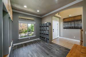 Foyer with crown molding, a textured ceiling, and hardwood / wood-style flooring