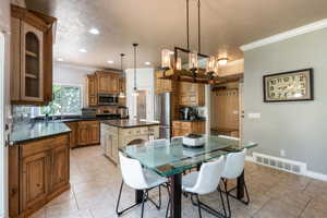 Tiled dining area featuring crown molding, sink, and a textured ceiling