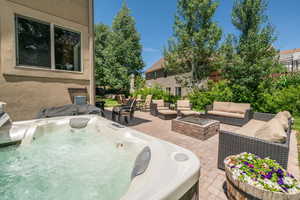 View of swimming pool with a hot tub, a patio, and an outdoor living space with a fire pit