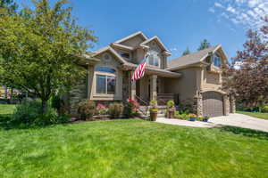 View of front of property with a garage, a front lawn, and covered porch