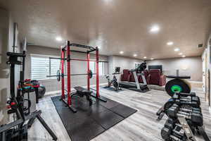 Exercise room featuring wood-type flooring and a textured ceiling