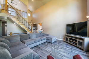 Living room with ceiling fan, hardwood / wood-style floors, and high vaulted ceiling