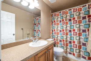 Bathroom featuring vanity, tile patterned flooring, toilet, and a textured ceiling