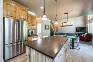 Kitchen featuring white cabinets, a kitchen bar, a center island, light tile patterned floors, and high end fridge