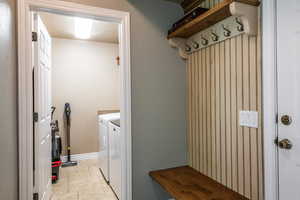 Washroom with washing machine and dryer, a textured ceiling, and light tile patterned floors