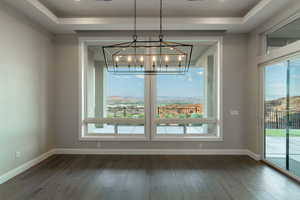 Unfurnished dining area featuring an inviting chandelier, a mountain view, a wealth of natural light, and dark hardwood / wood-style floors