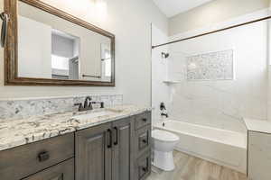 Full bathroom featuring tiled shower / bath combo, vanity, wood-type flooring, and toilet