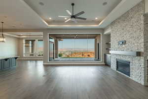 Unfurnished living room featuring a healthy amount of sunlight, a raised ceiling, and hardwood / wood-style floors