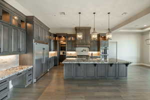 Kitchen featuring pendant lighting, sink, appliances with stainless steel finishes, a spacious island, and stone countertops