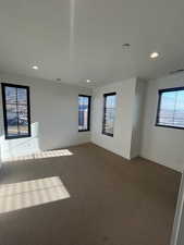 Unfurnished room featuring plenty of natural light and dark carpet