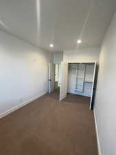 Unfurnished bedroom with dark carpet and a closet