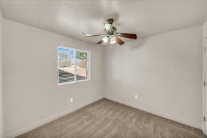 Carpeted spare room featuring ceiling fan