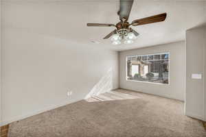 Spare room with ceiling fan, light colored carpet, and a textured ceiling