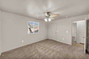 Empty room featuring ceiling fan, light carpet, and a textured ceiling