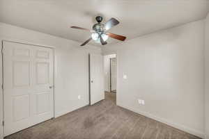 Unfurnished bedroom with ceiling fan and light colored carpet