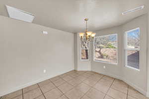 Unfurnished dining area with light tile patterned floors, a notable chandelier, and a textured ceiling