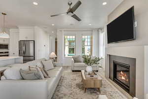 Living room with ceiling fan, light hardwood / wood-style floors, and a tiled fireplace