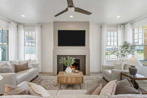 Living room with ceiling fan, a fireplace, and light wood-type flooring