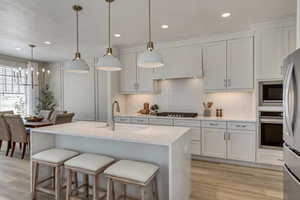 Kitchen with appliances with stainless steel finishes, white cabinetry, hanging light fixtures, and sink