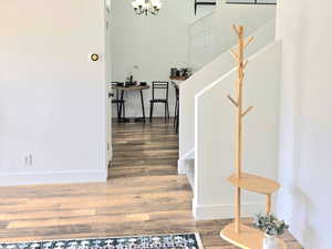 Stairs with a notable chandelier, wood-type flooring, and vaulted ceiling