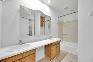 Bathroom with vanity, tub / shower combination, and tile patterned flooring