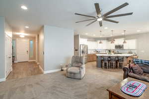 Living room featuring light carpet and ceiling fan