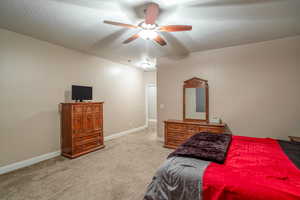 Carpeted bedroom featuring ceiling fan and a textured ceiling