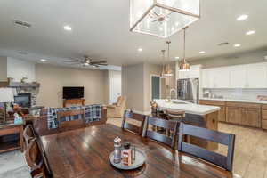 Dining area featuring sink, a stone fireplace, light hardwood / wood-style floors, and ceiling fan