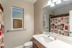 Bathroom with a shower with curtain, vanity, a chandelier, and toilet